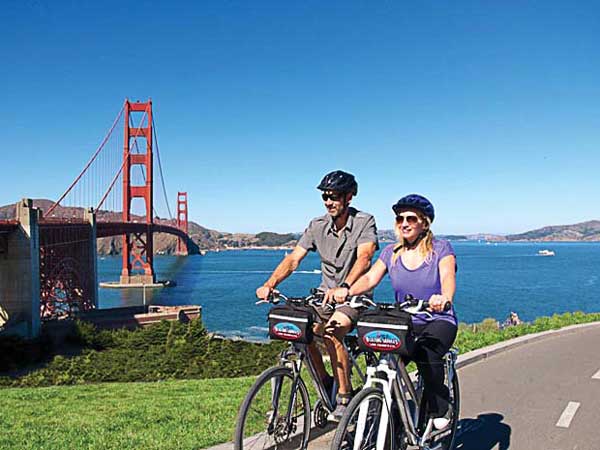Couple Biking By The Golden Gate Bridge.
