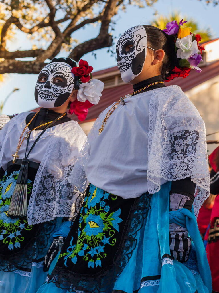 Dancers in Catrina sugar skull face paint and embroidered dresses at a Día de los Muertos celebration, a fall tradition to enjoy while staying at the Argonaut Hotel in San Francisco