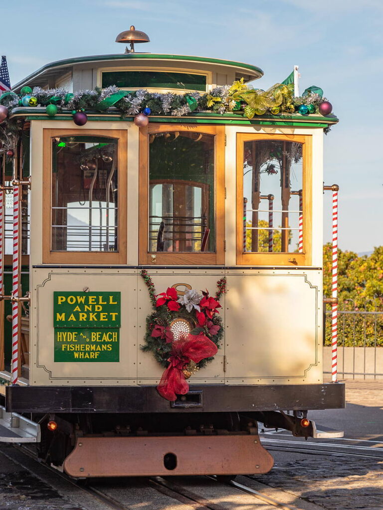 Powell-Hyde cable car decorated with holiday garland and a poinsettia wreath at the Hyde Street turnaround, steps from the Argonaut Hotel at Fisherman's Wharf in San Francisco