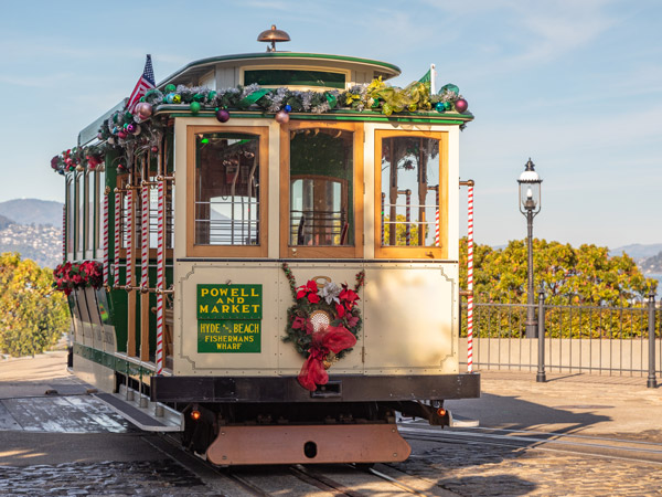 Historic Powell and Market cable car decorated with holiday garland and a poinsettia wreath at the Fisherman's Wharf turnaround near the Argonaut Hotel in San Francisco